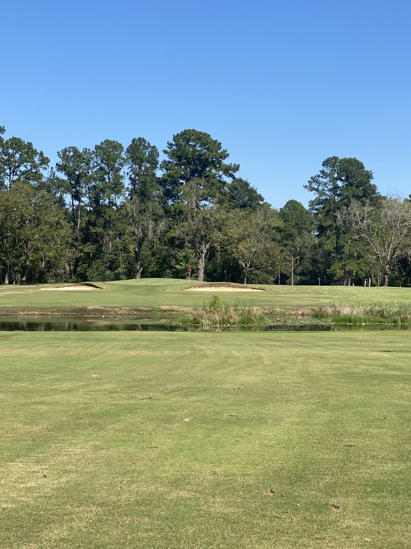 Green guarded by bunkers beyond the pond